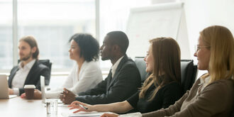 People sitting at a large table during a committee meeting.