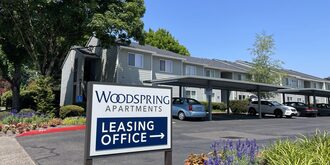 An external view of Woodspring Apartments' entrance and its leasing office sign