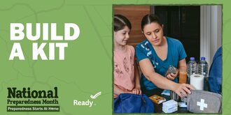 A mother and daughter sit at a kitchen table that is covered in preparedness supplies like a first aid kit, toilet paper, and water bottles
