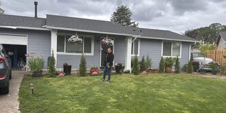 View of a woman standing in front of her house on the lawn