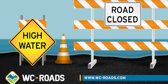 Barricade and signs that say "High Water" and "Road Closed"