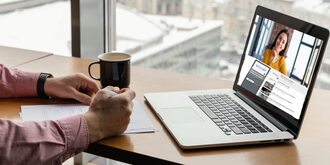 Person using a laptop computer taking notes with a coffee cup