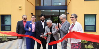 Community leaders cut a ribbon in front of the building