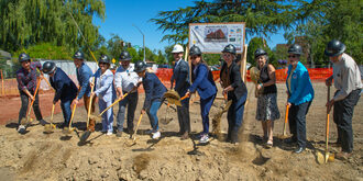 A group of people lined up with shovels in the ground.