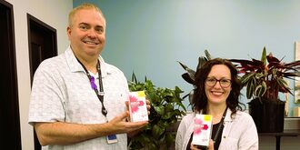 Man and woman smiling holding boxes of naloxone