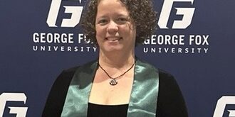 A woman posing infront a George Fox University background