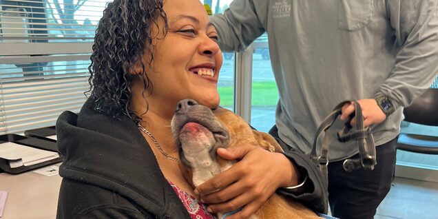 Happy woman embracing dog's face next to her own 