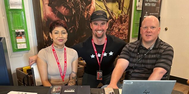 Three smiling staff at deflection outreach table