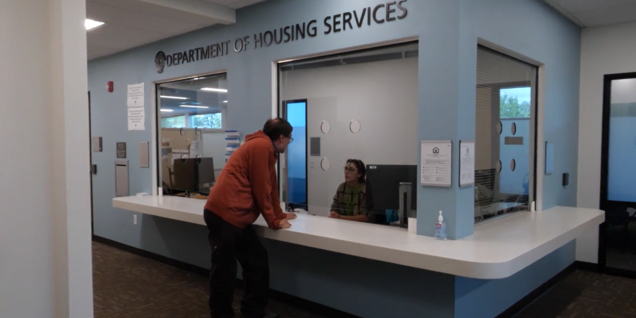 A man leaning on a reception desk in a lobby room