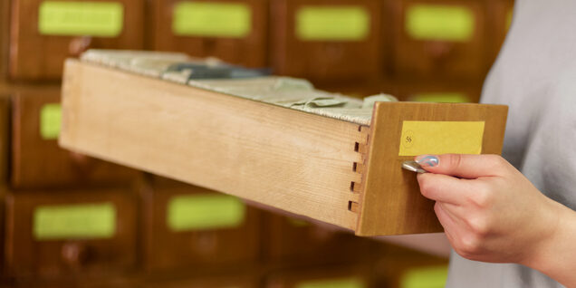 Person holding the drawer of a card catalog