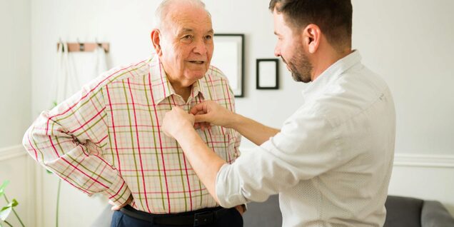 Older man receives help getting dressed