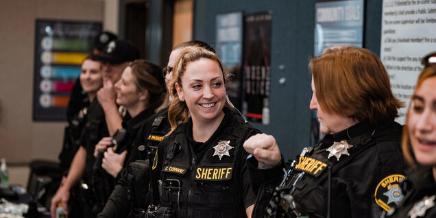 Officers standing in line in front of a table smiling