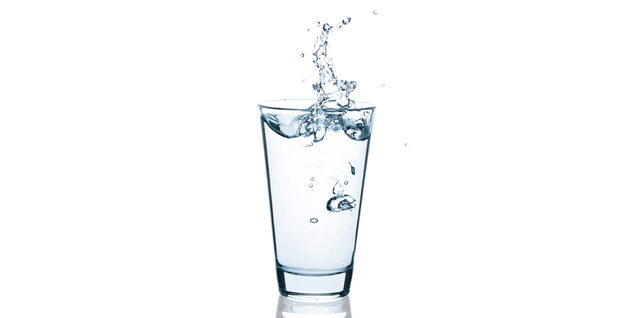 A glass of water on a white background splashed upward