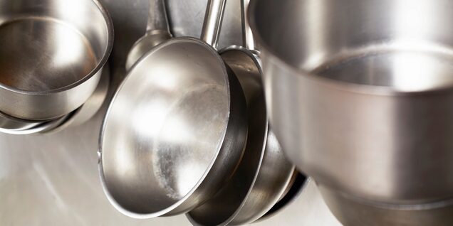 stainless steel pots and pans hang in restaurant kitchen