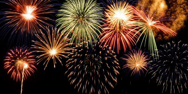 A dark night sky lit up with gold and green fireworks