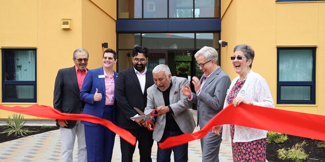 Community leaders cut a ribbon in front of the building