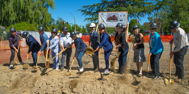 A group of people lined up with shovels in the ground.