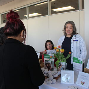 Four people engage in conversation with a table of signs in between them. 
