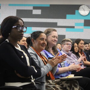 A group of people sitting down while clapping their hands. 