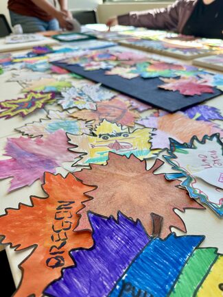 DD community art project of colored leaves and hands being assembled on canvases by volunteers