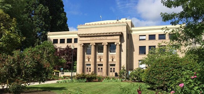 Washington County Courthouse on a sunny day surrounded by green trees, shrubs and flowers.