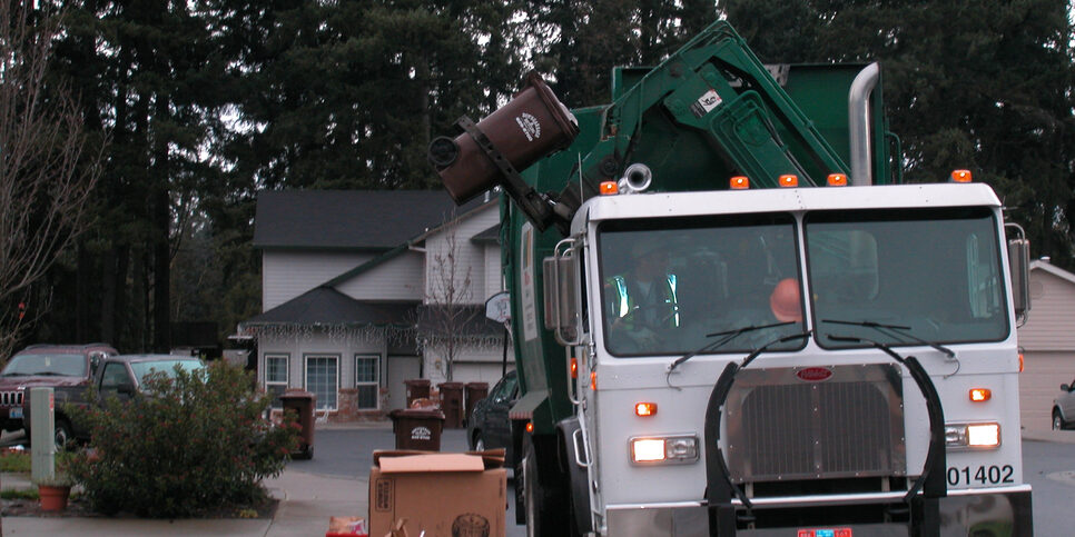 Garbage truck dumps bin into collection container