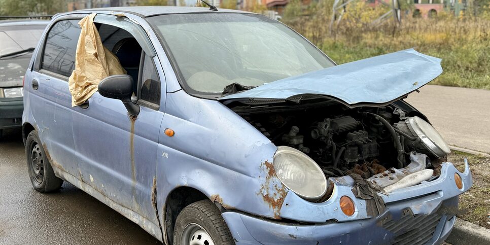 Wrecked and rusted car with hood open