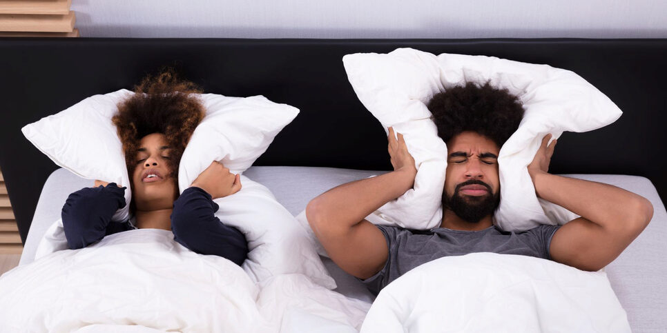 Couple in bed covers ears with pillows